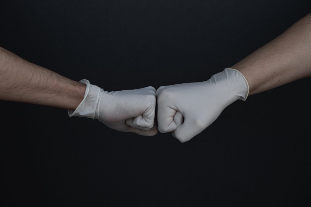 Photo of two hands in latex gloves pounding each other