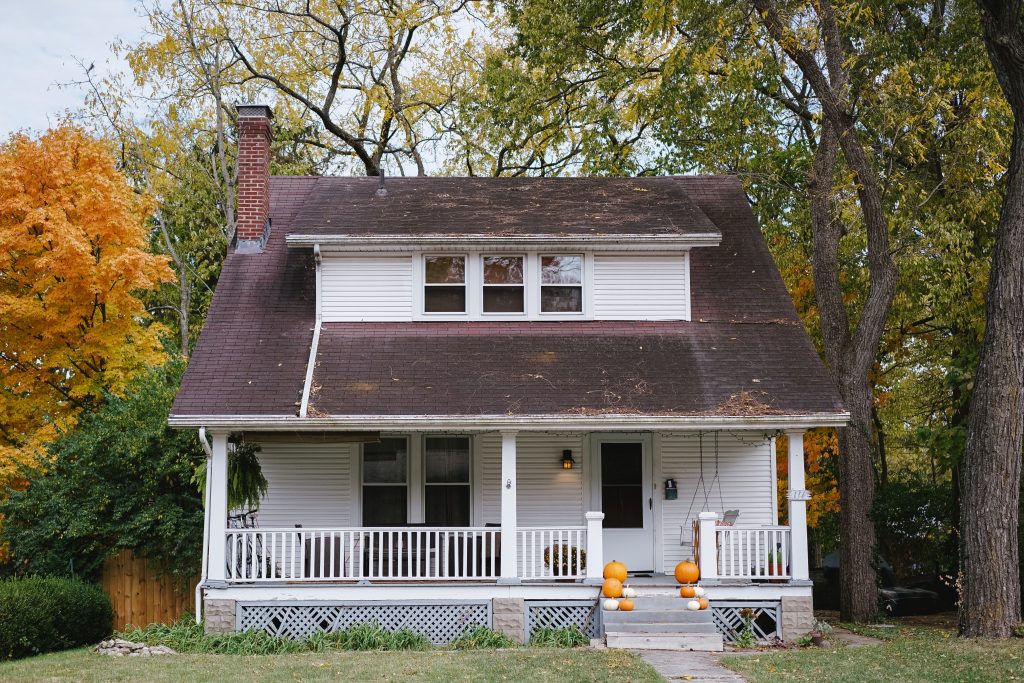 Photo of a white house with a front-porch and pumpkins on the steps