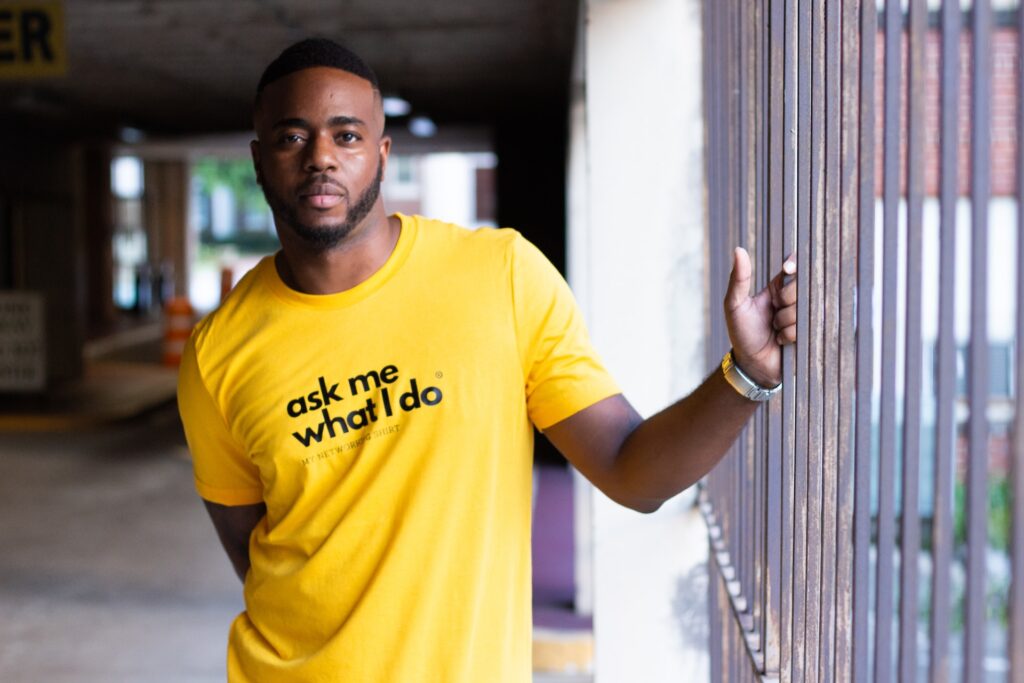 Young man in a yellow t-shirt that says "Ask me what I do"